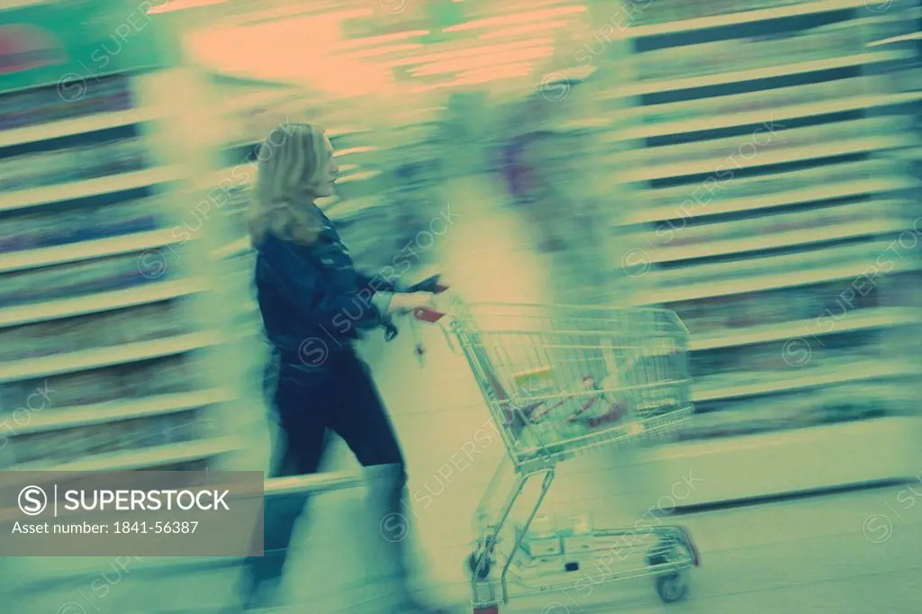 Side view of a woman pushing a trolley in a supermarket, Germany, Europe