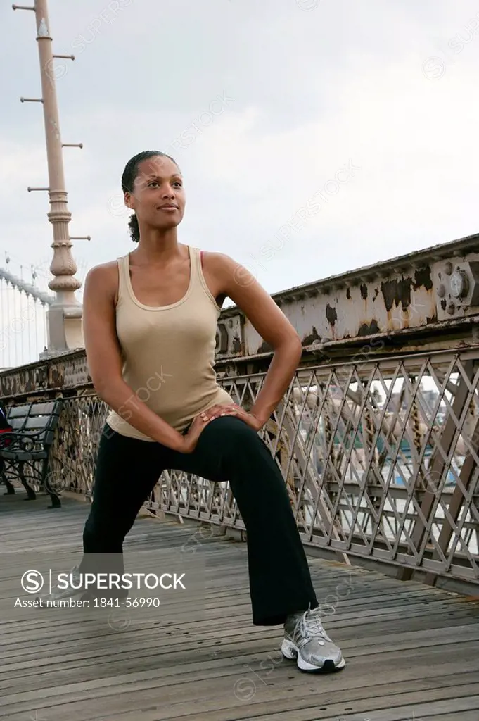 Woman standing on Brooklyn Bridge and stretching, New York City, USA, low angle view