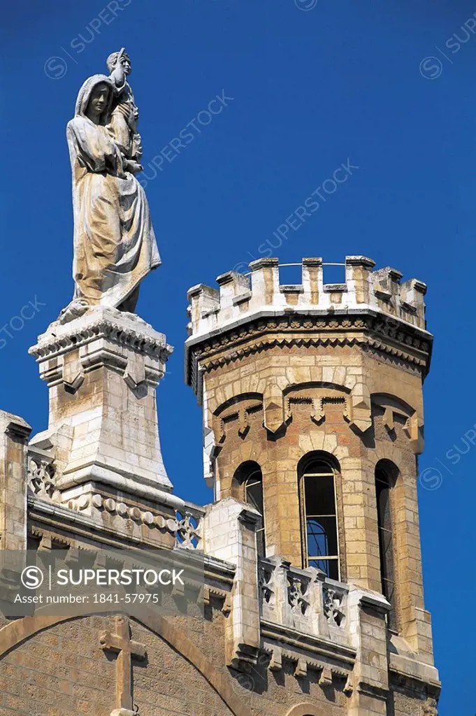 Jesus statue on top of church against blue sky
