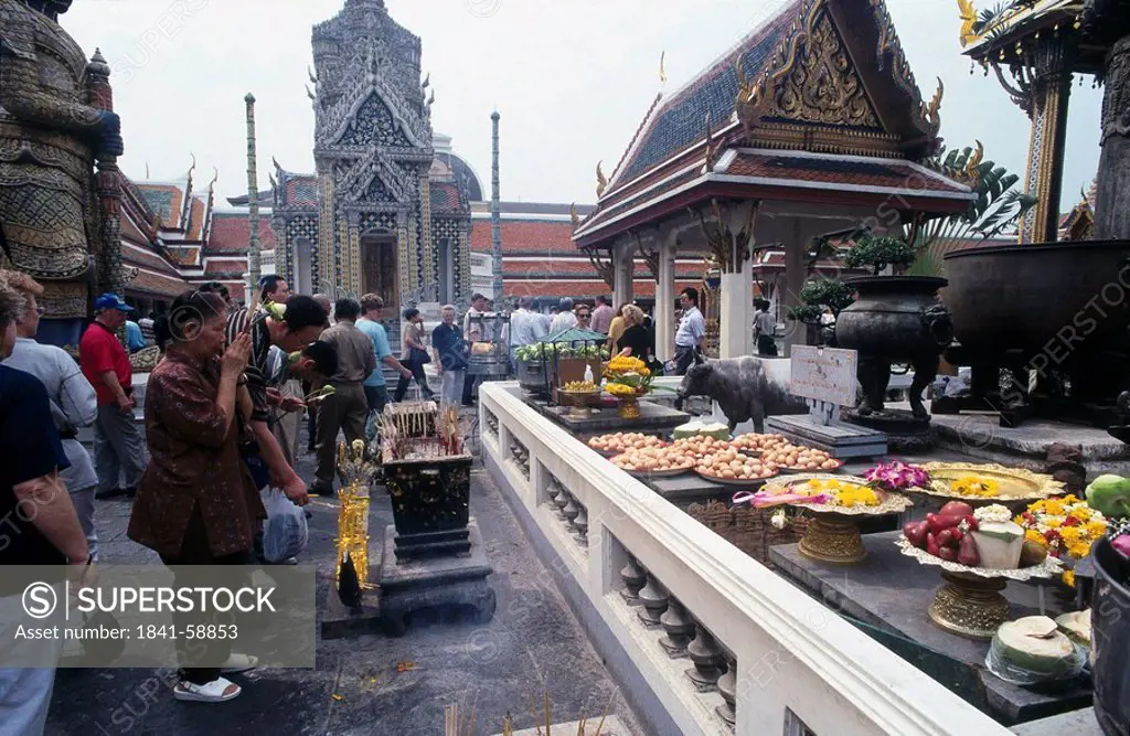 People making religious offering at temple, Wat Phra Kaeo, Bangkok, Thailand