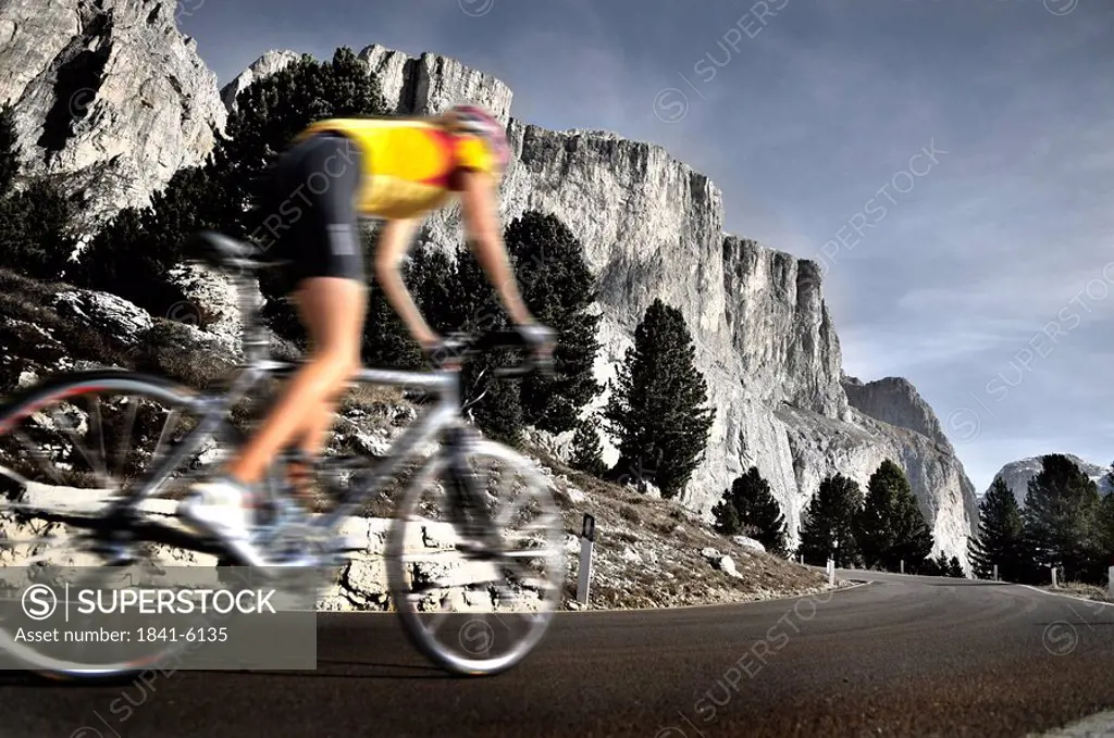 Mountain biker in motion on country road, Dolomites, Italy
