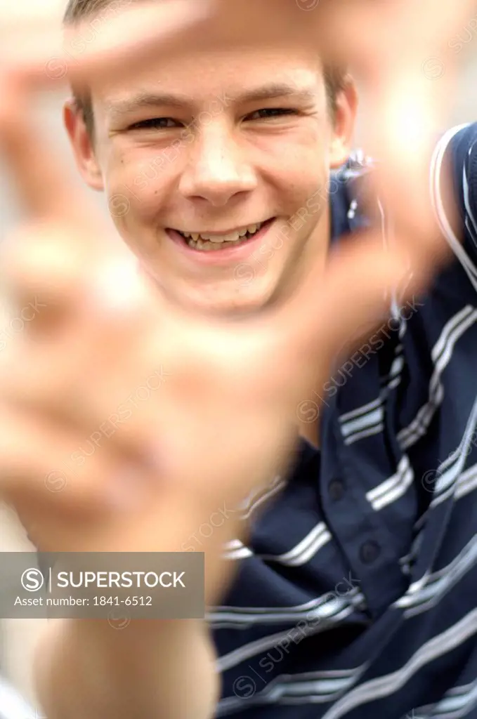 Portrait of teenage boy looking through finger frame