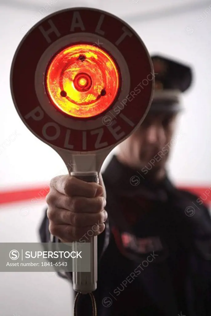 Close_up of policeman holding signaling disc