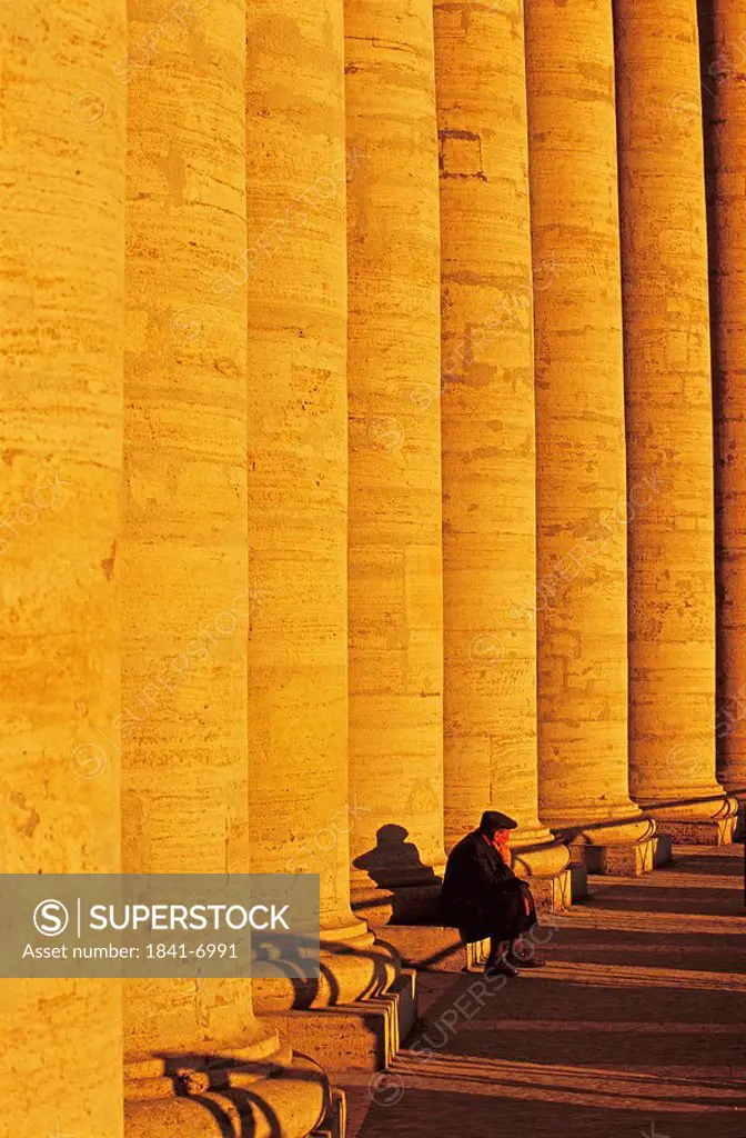 Tourist sitting near colonnade, Berninis Colonnade, St. Peters Square, Vatican City, Rome, Italy