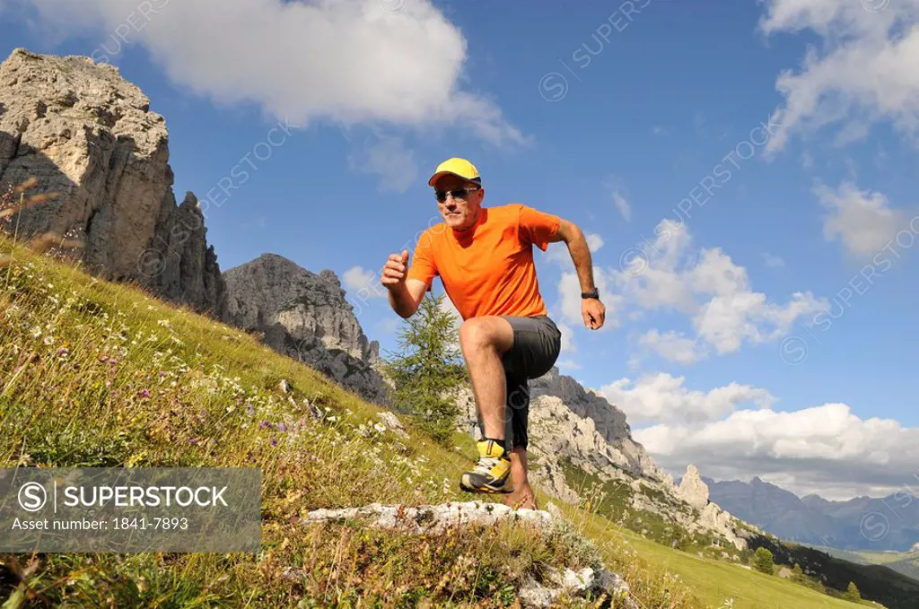 Low angle view of mature man running on landscape, Trentino_Alto Adige, Italy