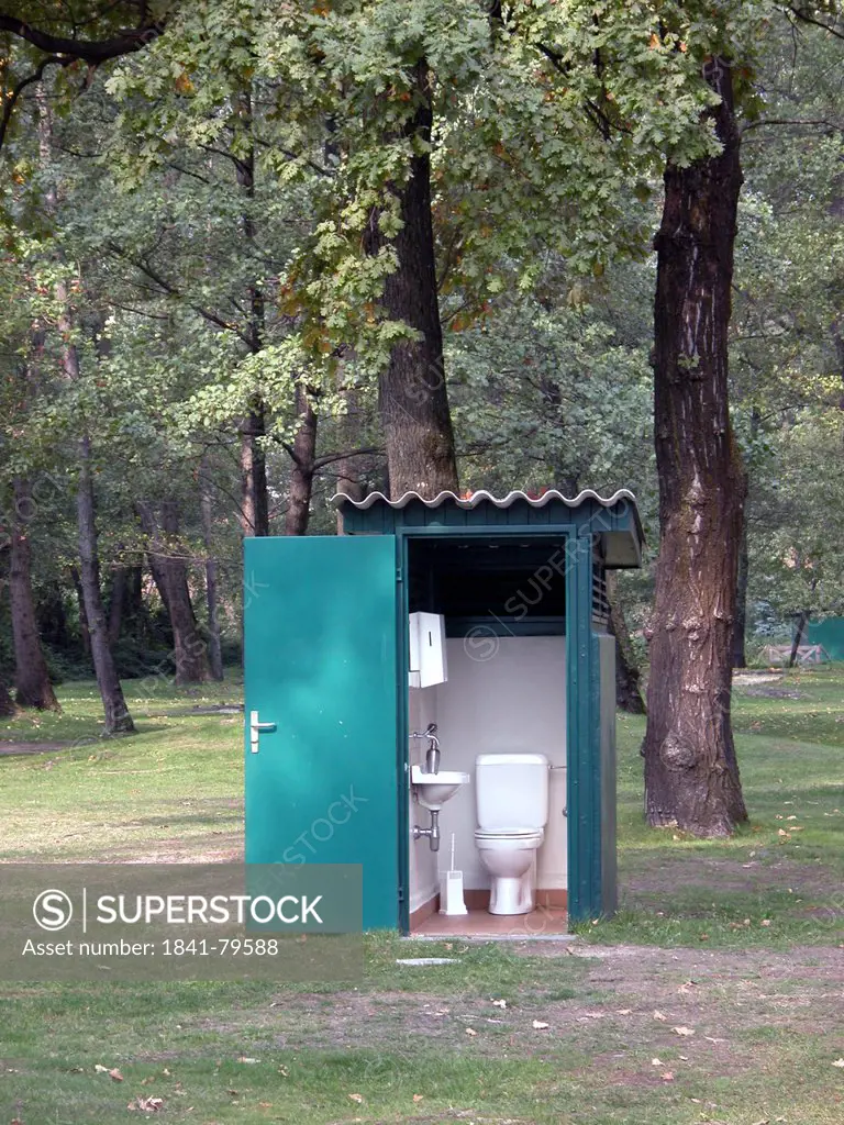 Open door of public toilet in forest