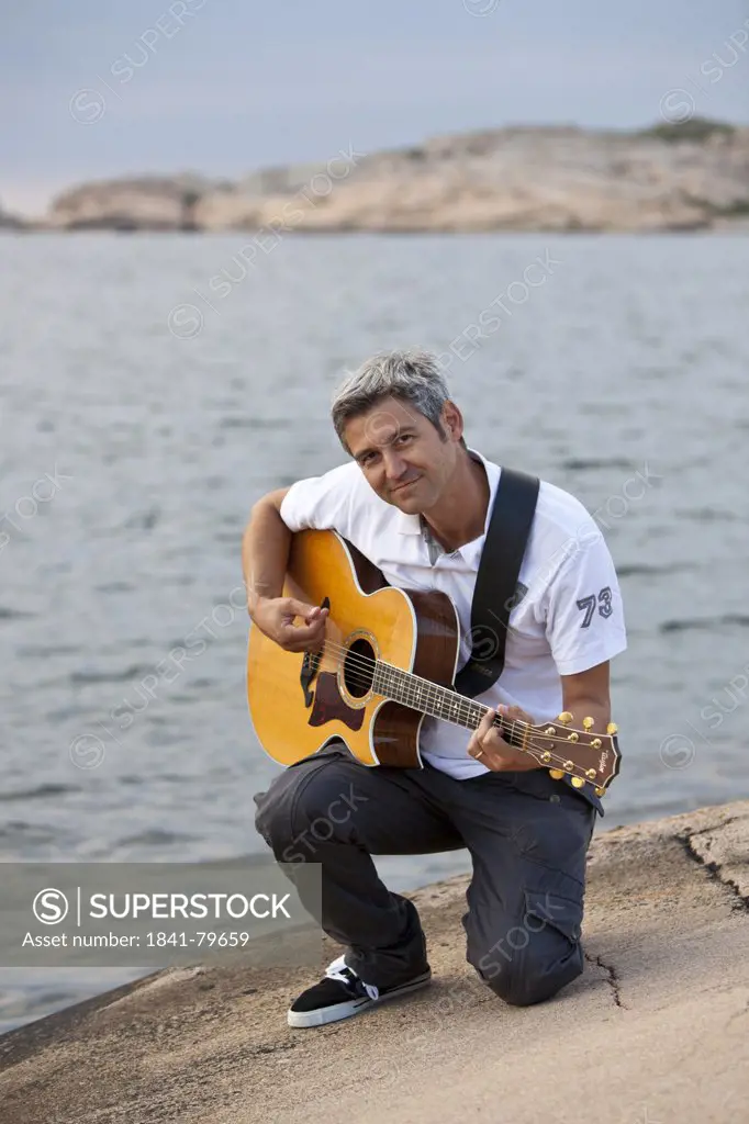Man playing guitar at the skerry coast in Sotenaes, Sweden