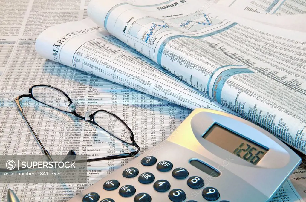 Close_up of financial newspapers with eyeglass and calculator