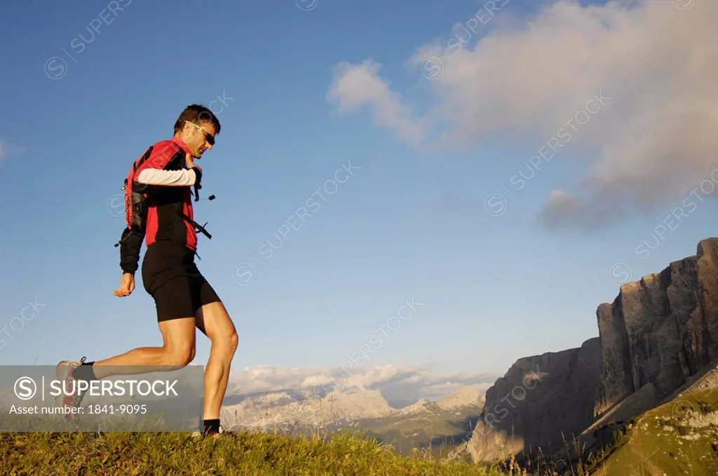 Side profile of mid adult man running on landscape, Trentino_Alto Adige, Italy