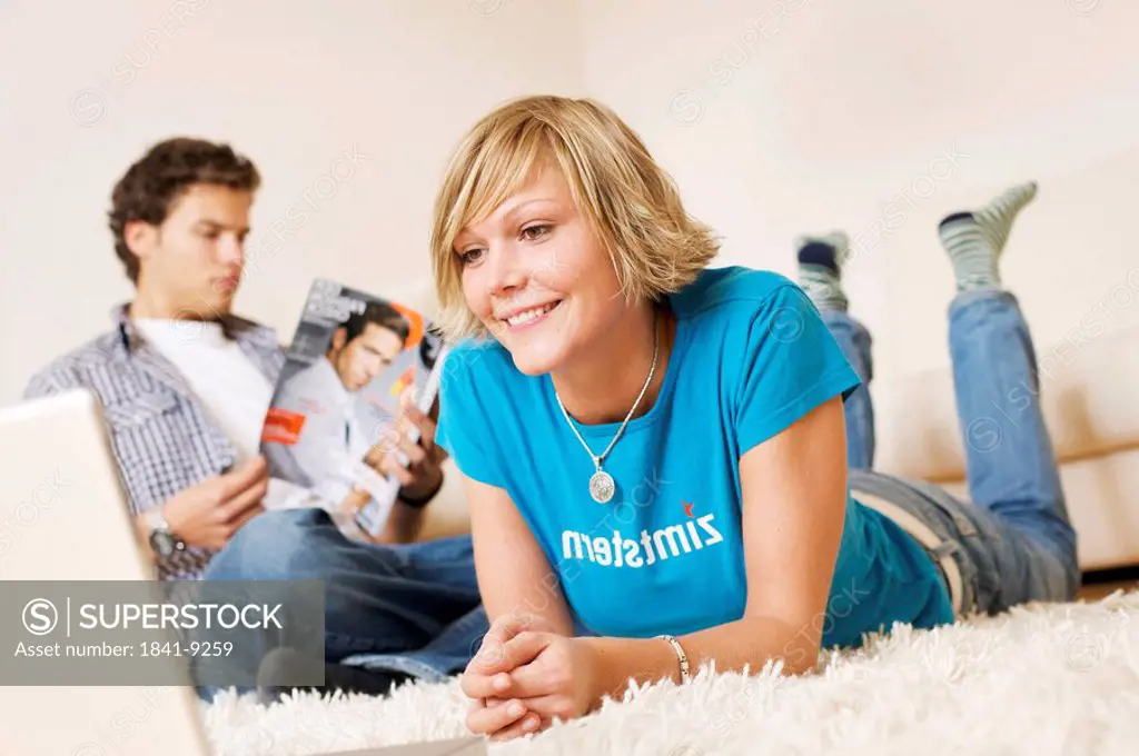 Teenager couple using media in living room, slanted view
