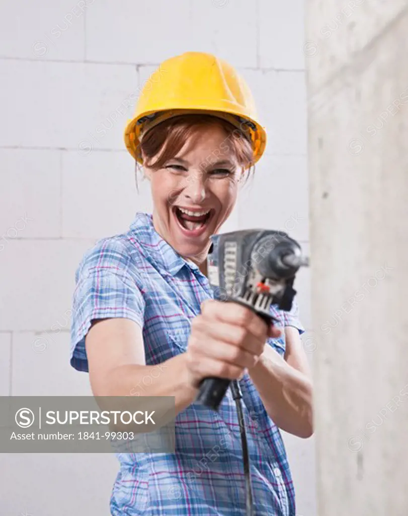Laughing woman with helmet and drill