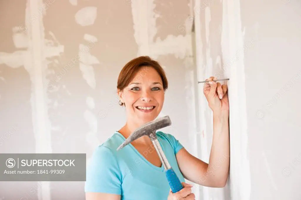 Woman hammering nail into wall