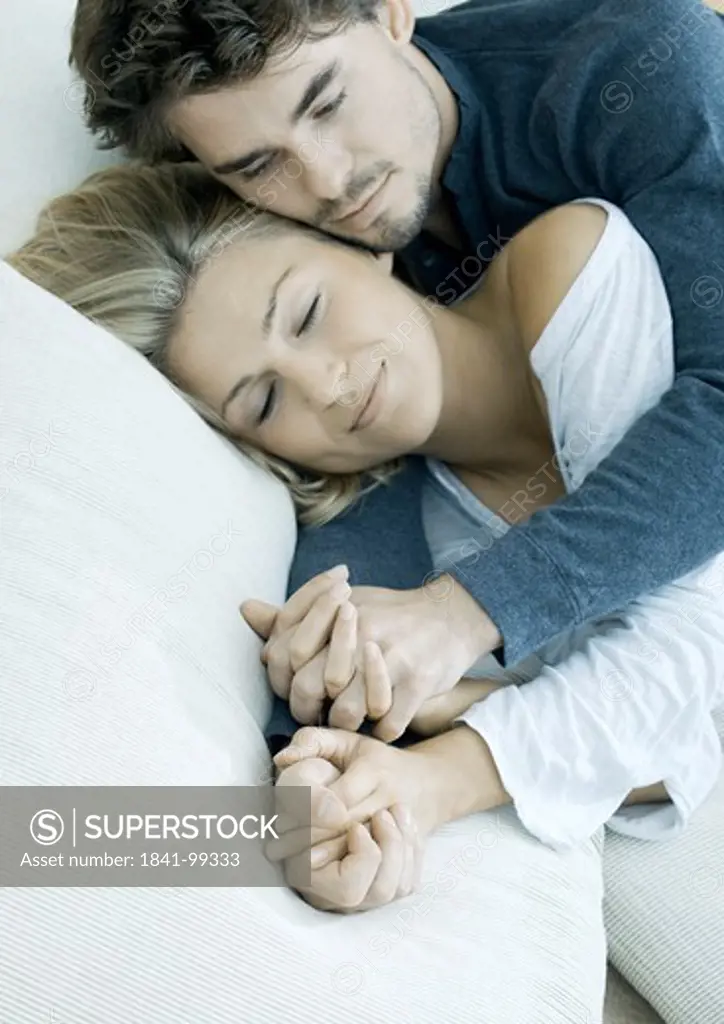 Young couple lying hand in hand in bed