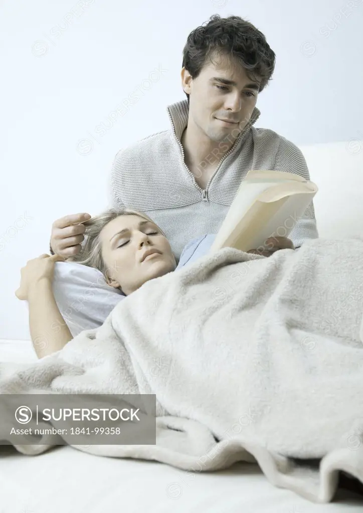 Young couple on bed reading book