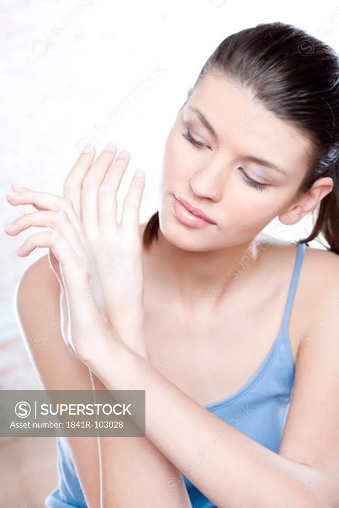 young woman putting cream on hands
