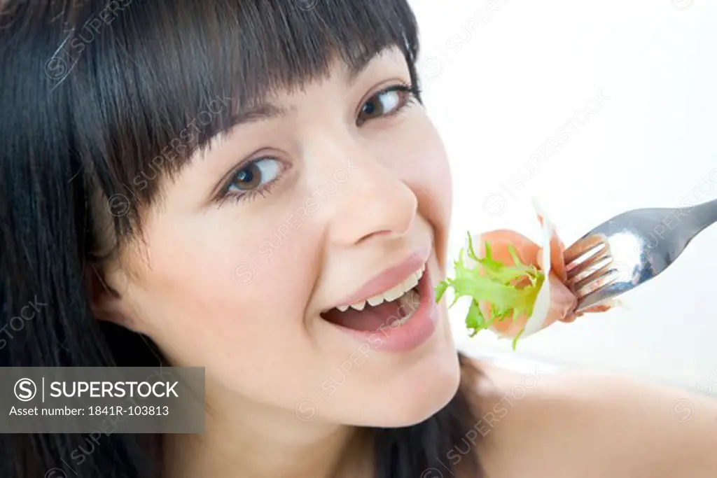 woman eating lettuce with slice of ham