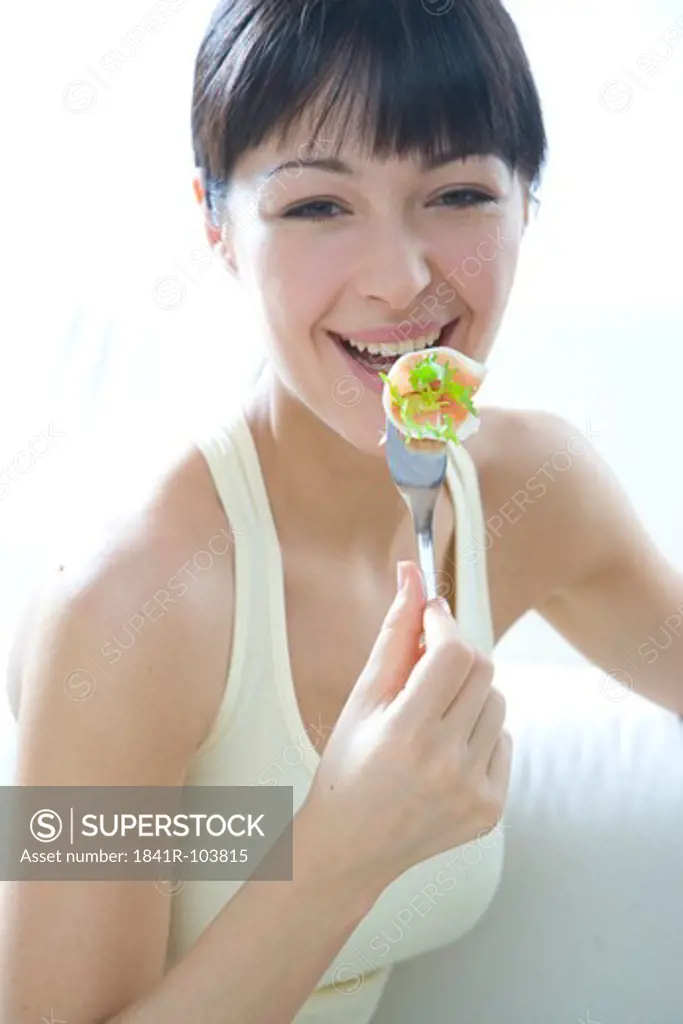 woman eating lettuce with slice of ham