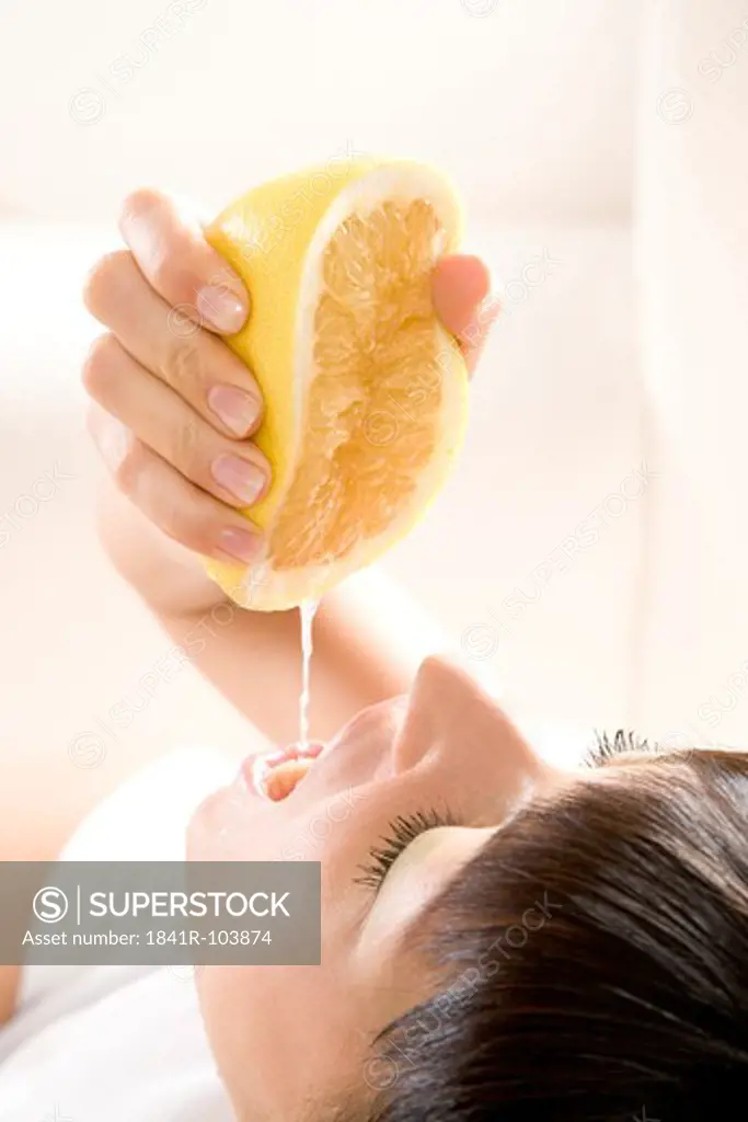 woman squeezing grapefruit juice into mouth