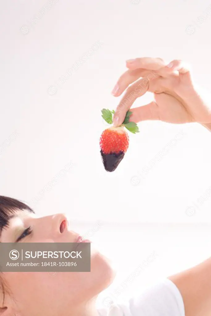 woman eating strawberry in chocolate