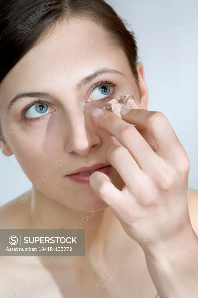 young woman touching face with ice cube
