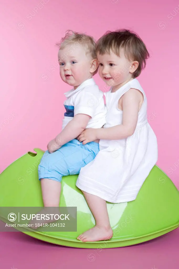 two toddlers sitting on toy