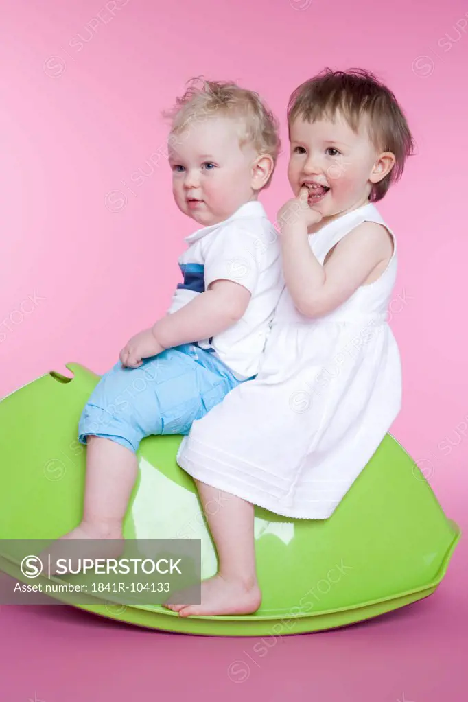 two toddlers sitting on toy