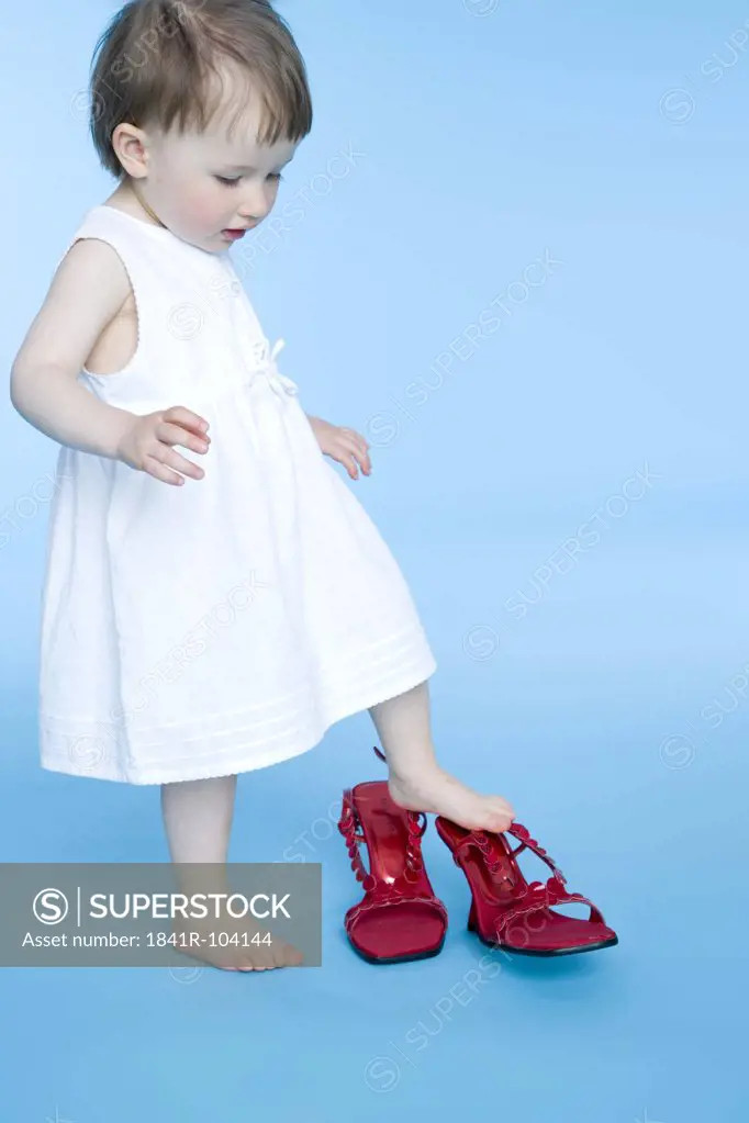 small girl trying on mother's shoes