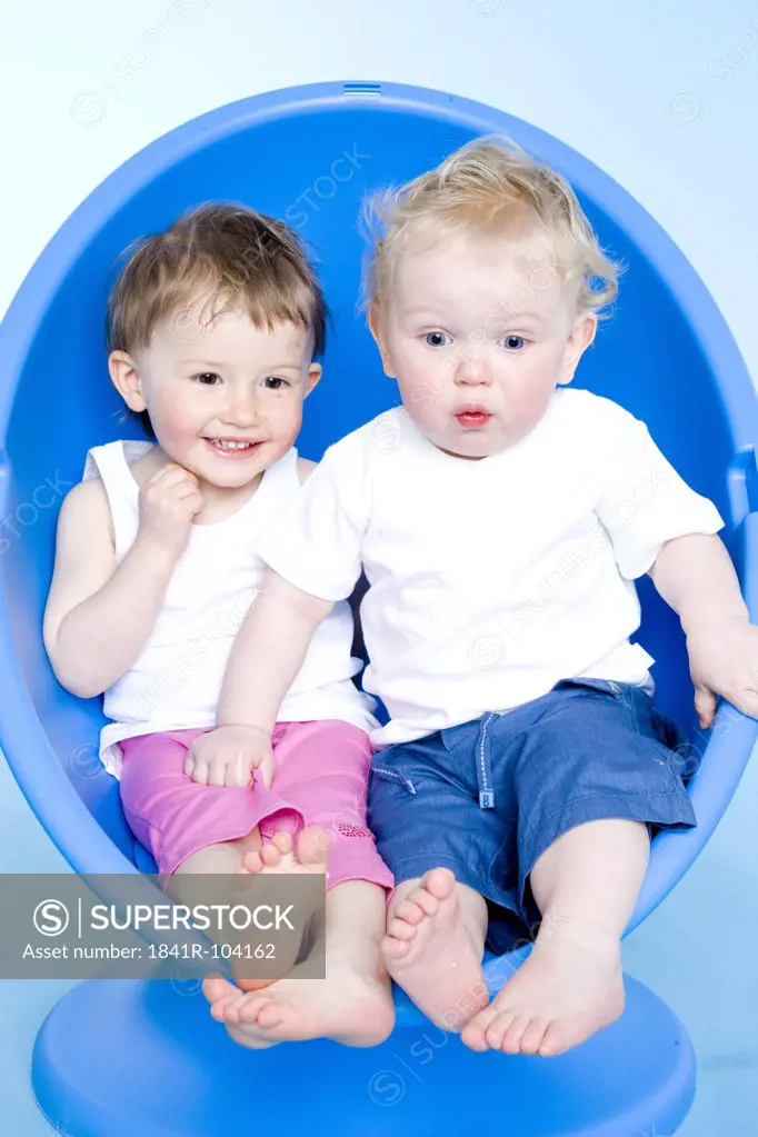 baby boy and baby girl sitting on chair