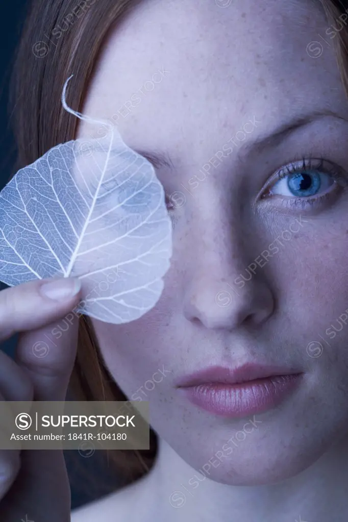 woman covering eye with leaf