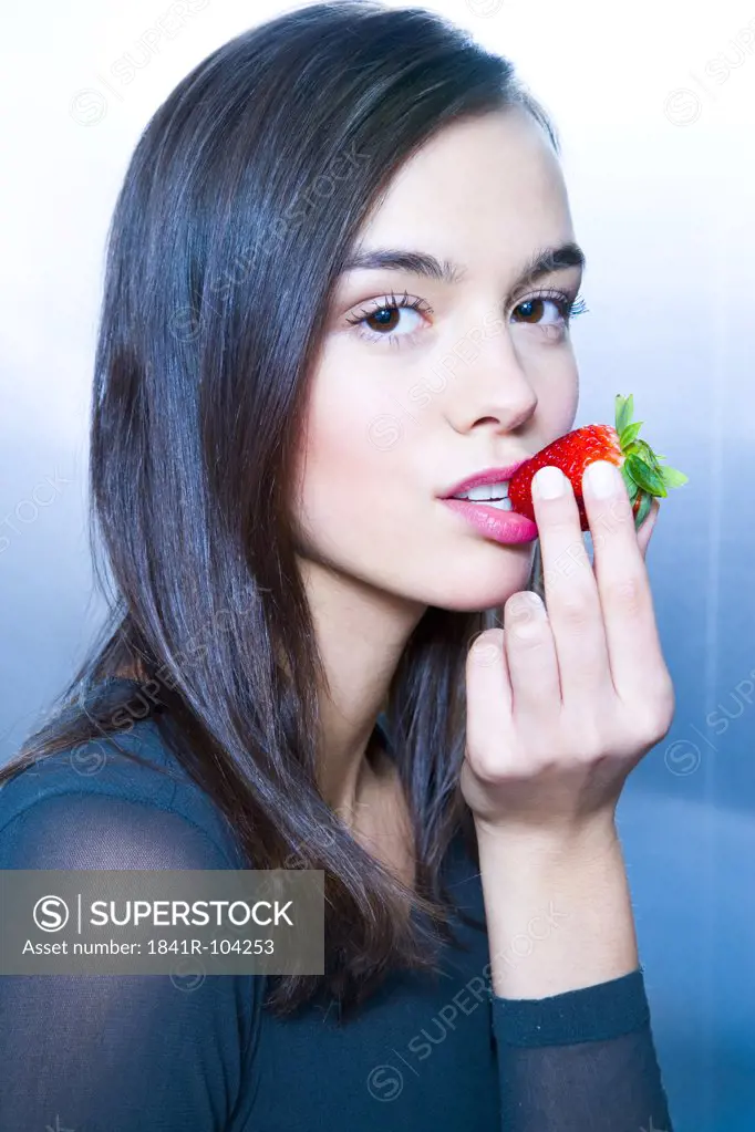 young woman with strawberry in mouth