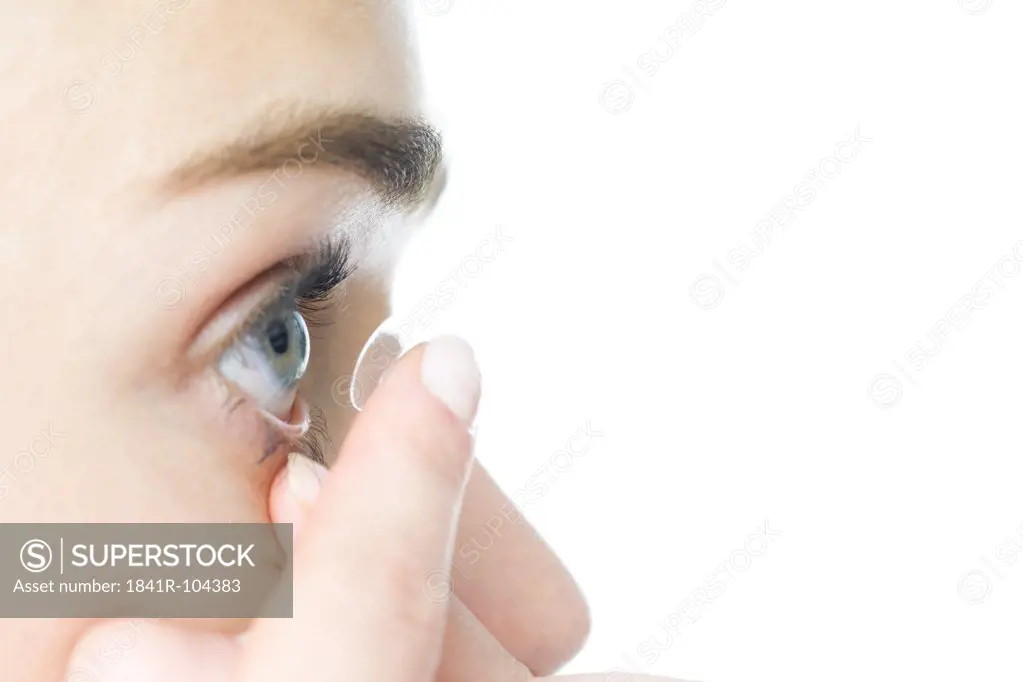 young woman putting on eye lenses