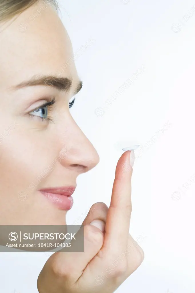 young woman putting on eye lenses