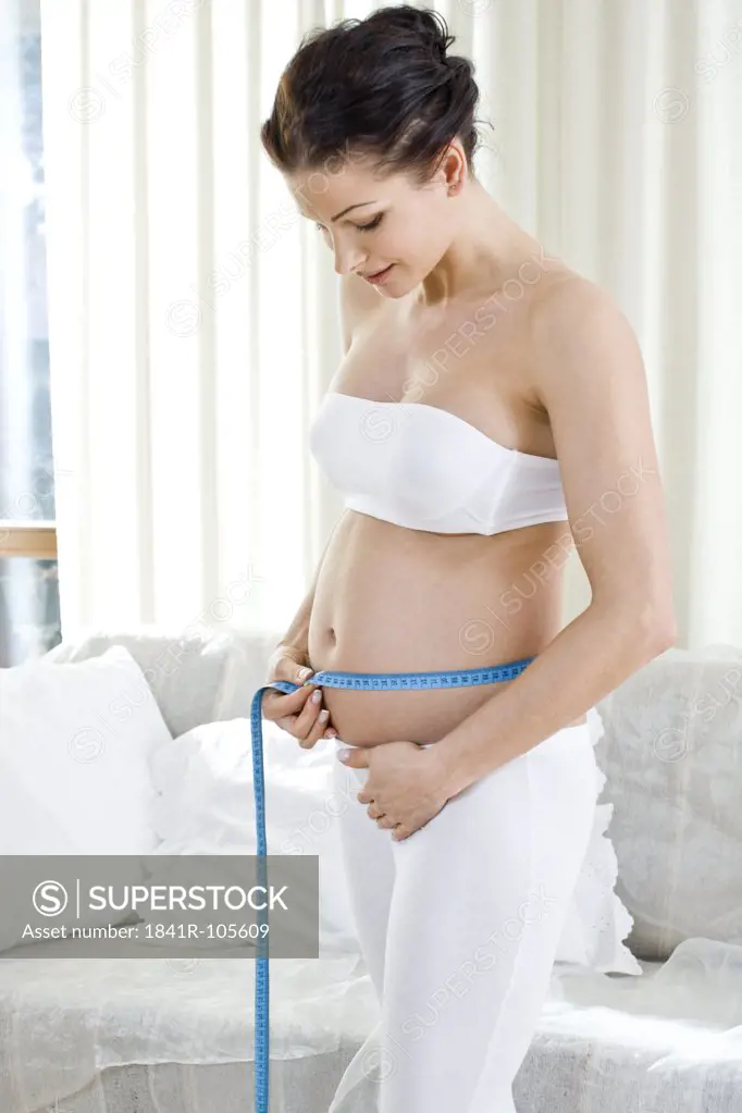 pregnant woman measuring her belly