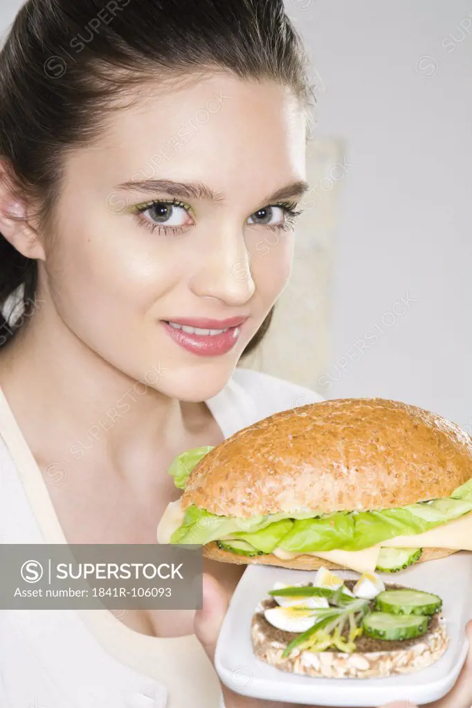 Young woman holding plate with sandwiches