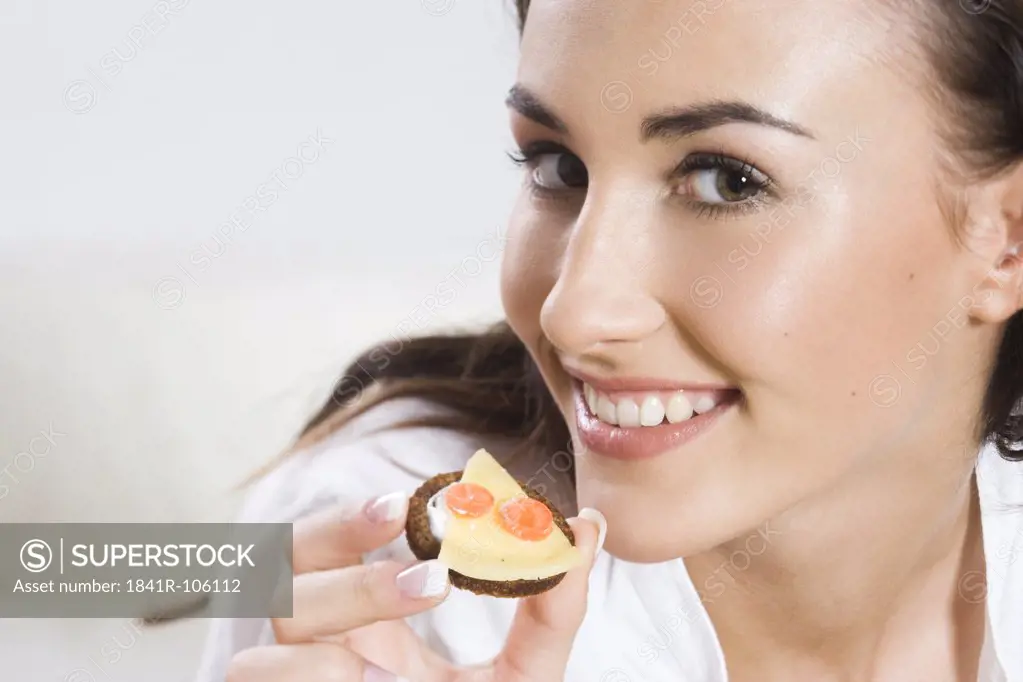 Young woman eating sandwich with cheese
