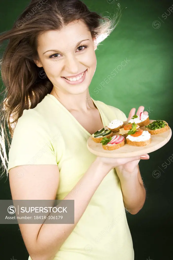 Young woman holding plate with sandwiches