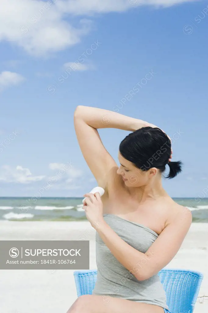 woman using deodrant on beach