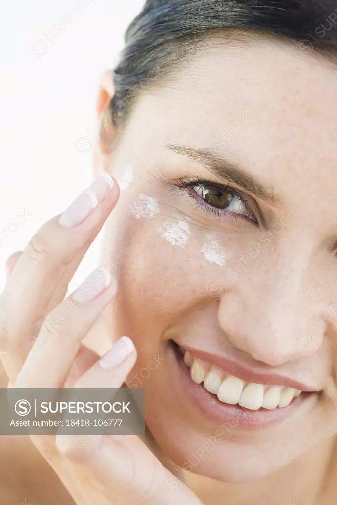 woman creaming face on beach