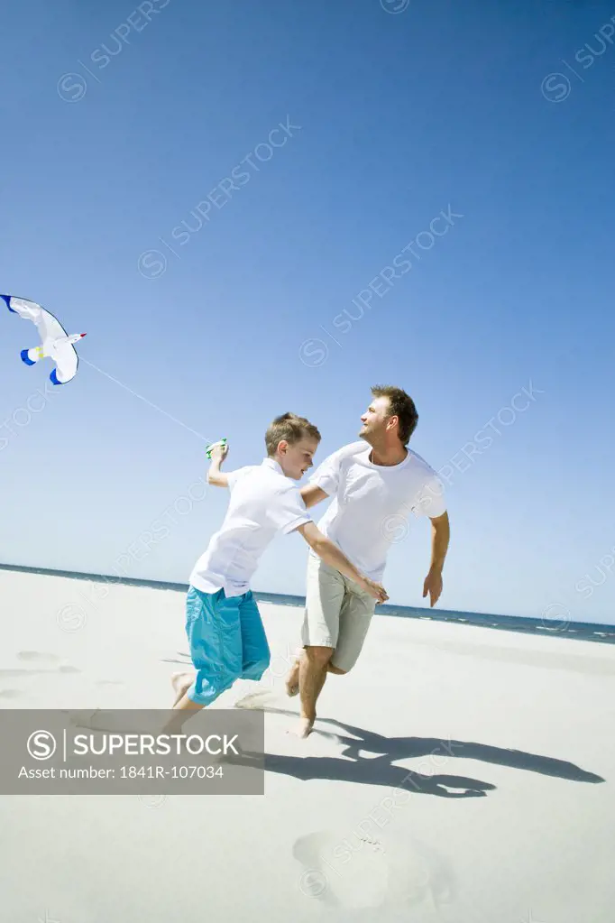 father and son playing with kite on beach