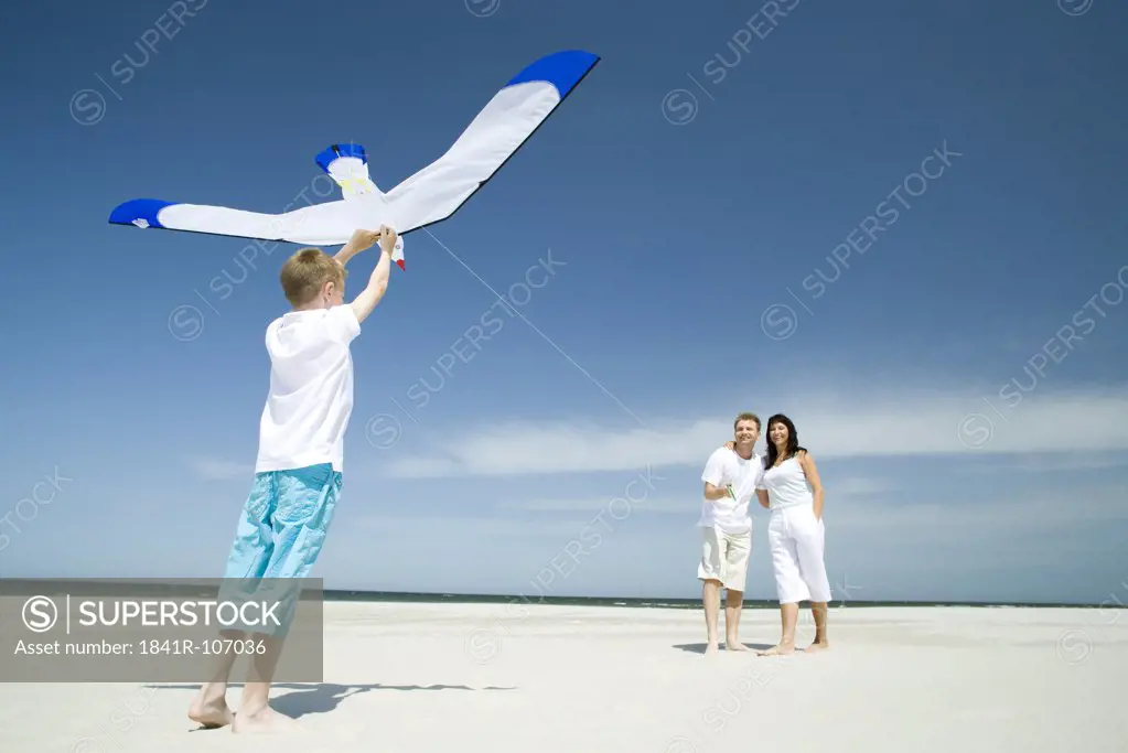 family playing with kite on beach