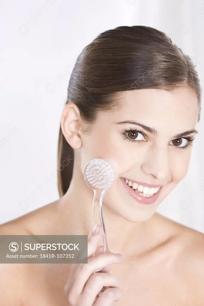 young woman massaging face with brush