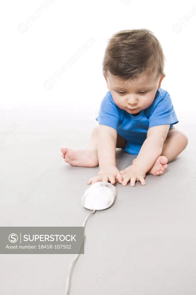 Baby on floor playing with computer mouse
