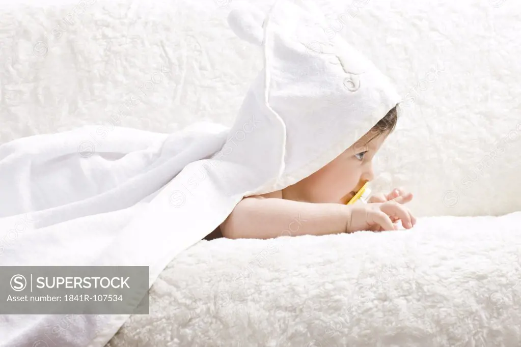 Baby in towel lying on sofa