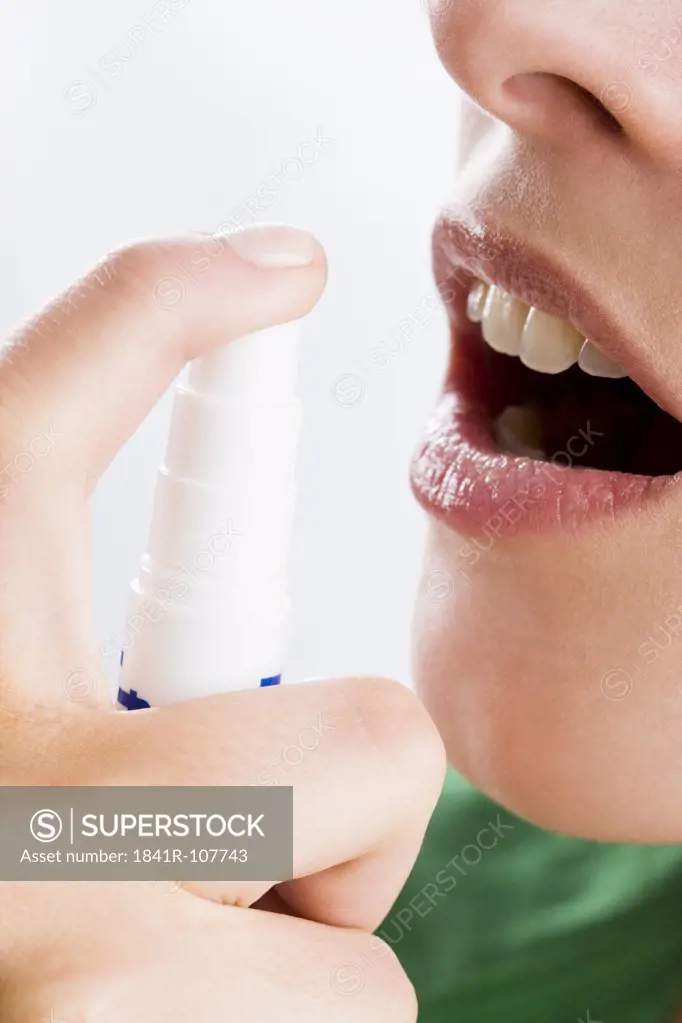 young woman using mouth freshener
