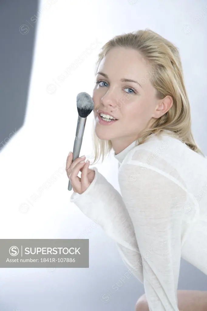 young woman applying powder on face