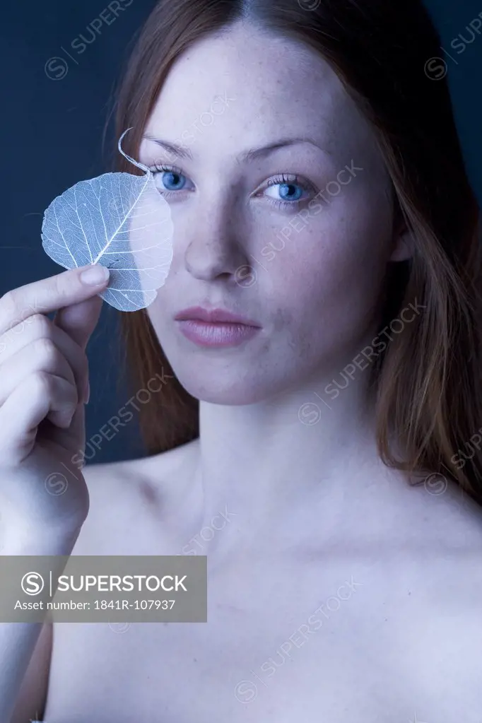 woman covering eye with leaf