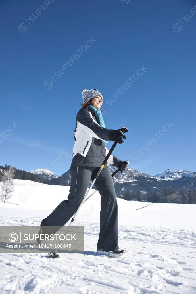 Smiling woman nordic walking in winter landscape, Tannheimer Tal, Tyrol, Austria