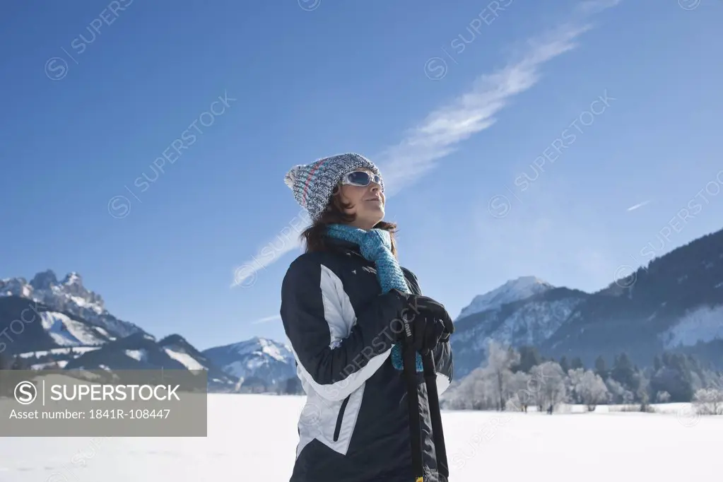 Smiling woman with nordic walking poles in winter landscape, Tannheimer Tal, Tyrol, Austria