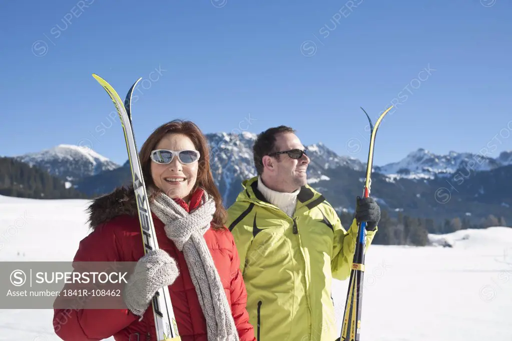Smiling couple with skis in winter landscape, Tannheimer Tal, Tyrol, Austria