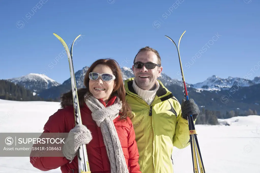 Smiling couple with skis in winter landscape, Tannheimer Tal, Tyrol, Austria
